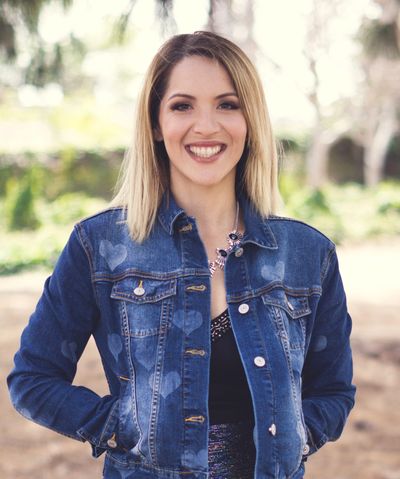 Smiling woman wearing a denim jacket outdoors.