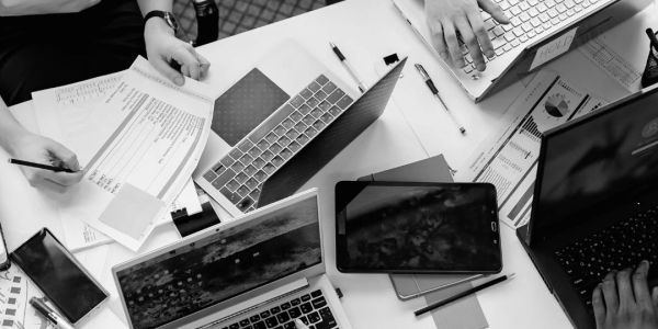 People working together using laptops, documents, and tablets in a collaborative workspace.