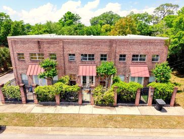 Brick building with pink awnings and greenery.