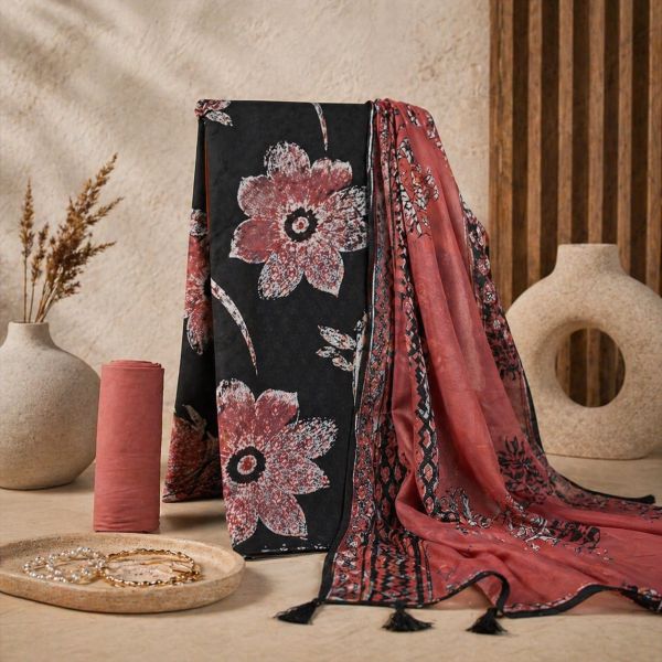 Elegant floral black and red fabric with accessories on a beige surface.