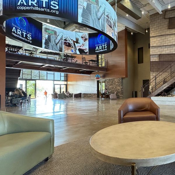 Atrium in between an arts center, coffee shop, and a church that features a round LED video halo dis