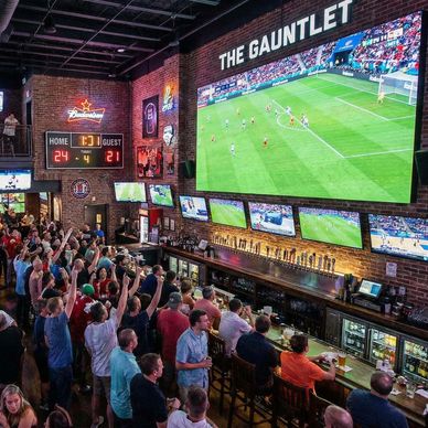 Large LED video display on the wall in a sports bar with lots of fans having a good time 