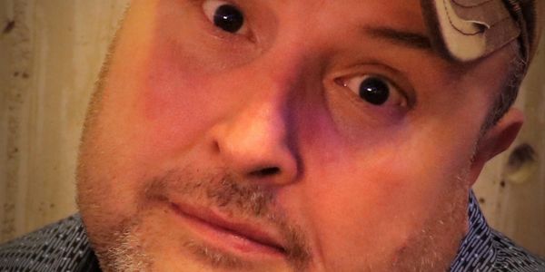 Close-up of a man with a cap looking directly at the camera.