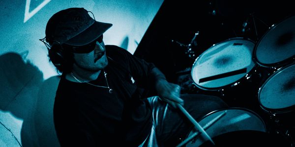 Man playing drums in a dark setting.