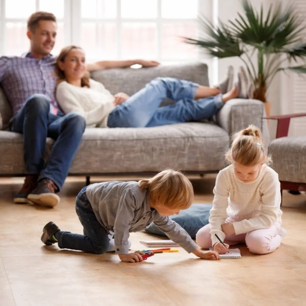 Children drawing on the floor while parents relax on a couch.