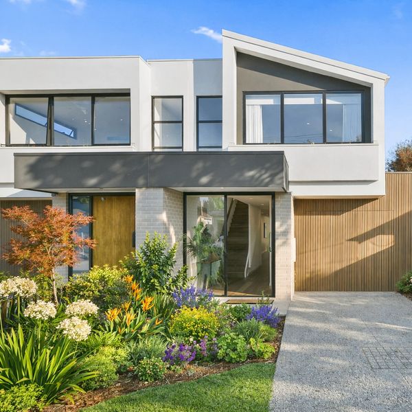 Modern two-story house with a vibrant garden and driveway.