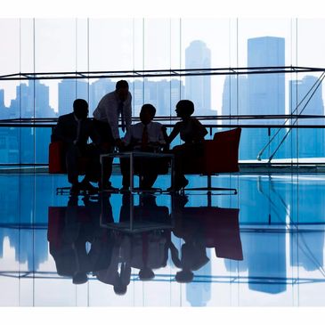 Silhouetted business team meeting in modern office with cityscape view.