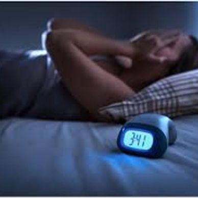 Person in bed unable to sleep, covering face, with clock showing 3:41 AM.