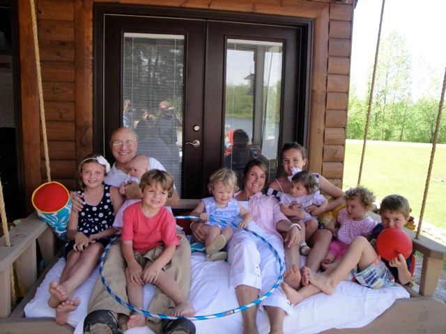 Family sitting on a hanging SwingBed on a porch