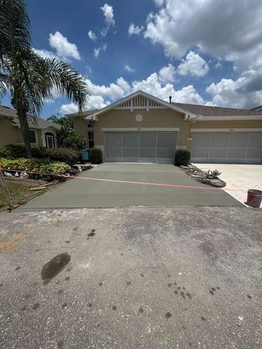 Newly poured concrete driveway drying in front of a house with a garage.