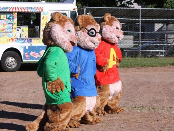 Three characters in chipmunk costumes stand side by side outdoors.