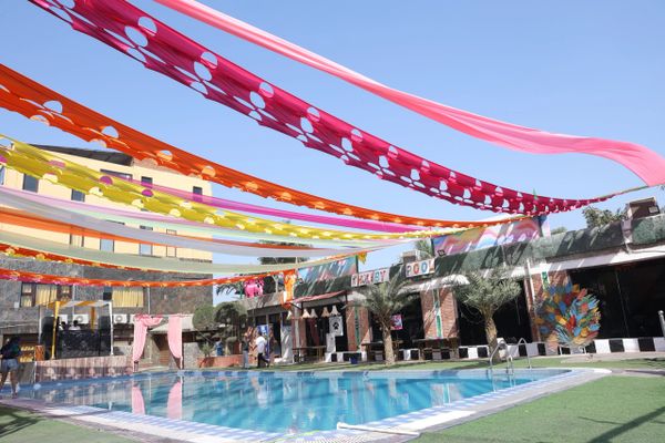 Decorative colorful fabric strips hang over an outdoor pool area under clear skies.