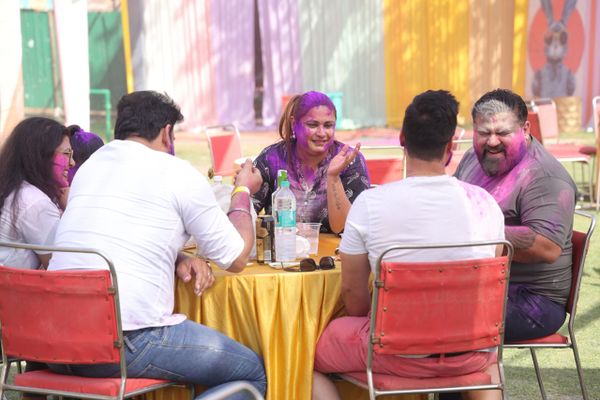 Group of friends enjoying Holi festival with vibrant colors and laughter.
