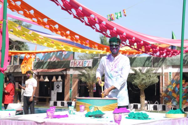 Man celebrating Holi with colorful powders under vibrant decorations.