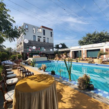 Elegant outdoor poolside setup with tables and chairs under a clear blue sky.