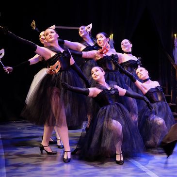 group of dancers wearing black costumes and holding masks
