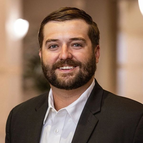 Smiling man in a suit jacket.