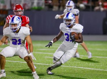 Football player in white running with the ball during a game.