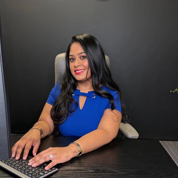 Woman in blue dress typing on a keyboard at a desk.
