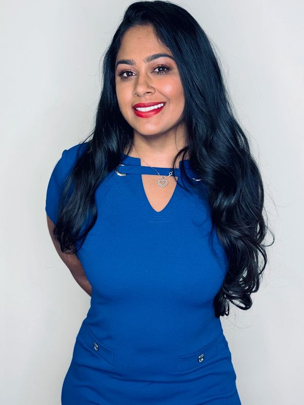 Smiling woman with long black hair in a blue dress.