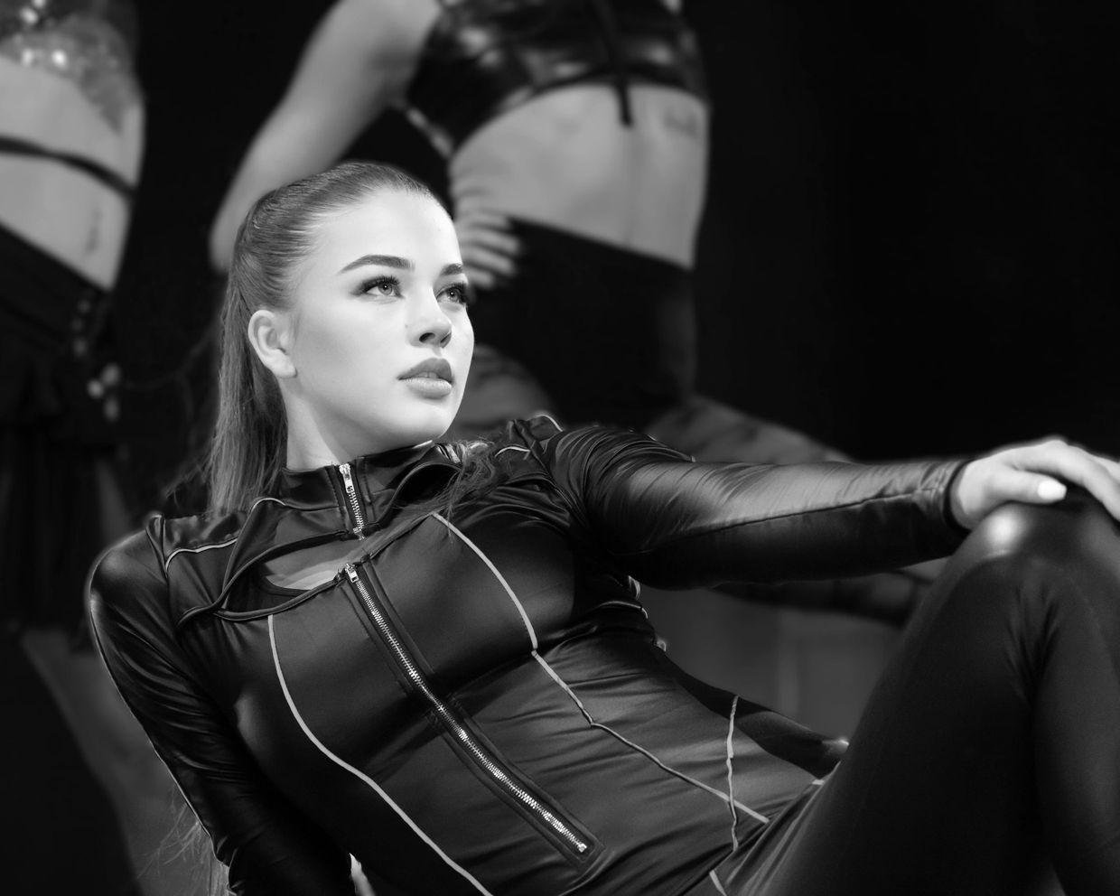 A focused dancer in a sleek black outfit poses gracefully on stage.