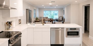 Kitchen remodeling with white cabinets, countertops, island,  crown molding and modern appliances 
