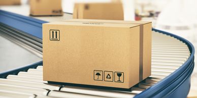 A cardboard box on a conveyor belt in a warehouse.
