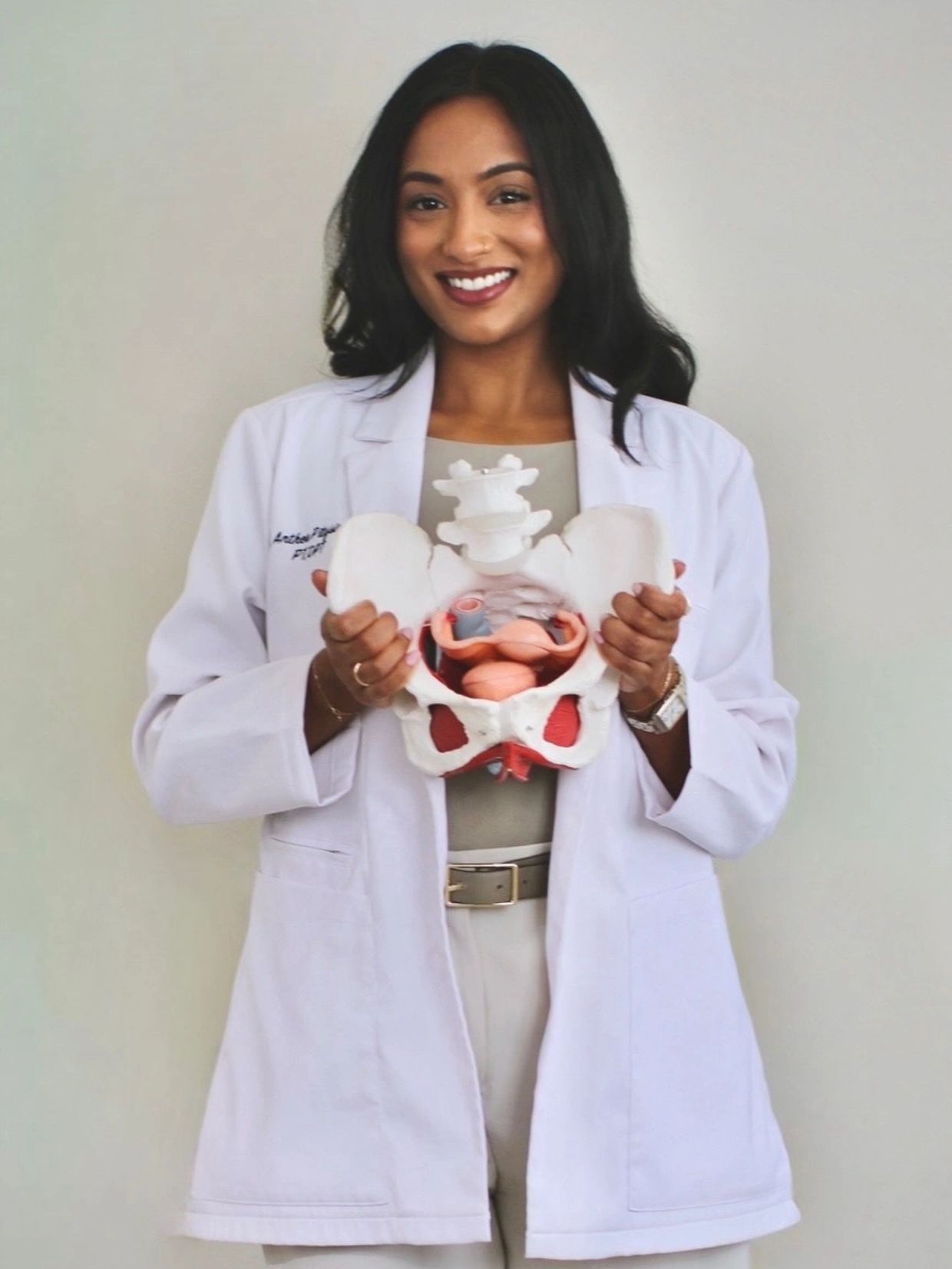 Pelvic health physical therapist demonstrating pelvic anatomy with a model in a white lab coat