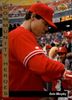 A man in a red sweatshirt and cap signing an autograph at a sports event.