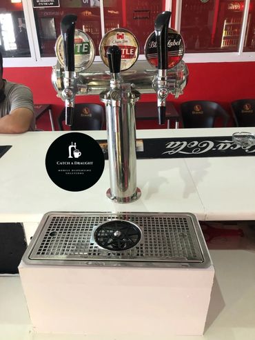 Beer dispenser tower on bar counter top with drip tray and under counter flash cooler