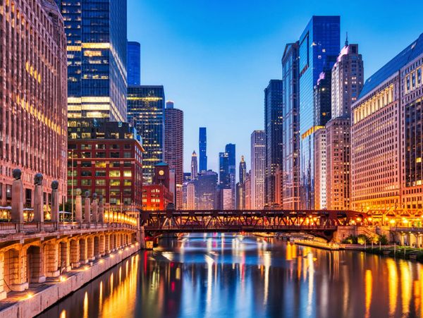 Chicago cityscape with river and illuminated buildings at dusk.