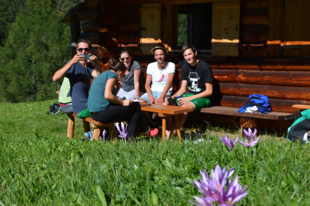 Group of people enjoying a sunny day outside a wooden cabin.