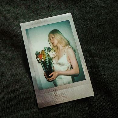 Polaroid photo of a woman in a satin dress holding colorful flowers.