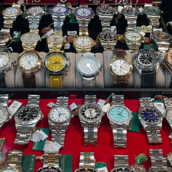 Luxury Rolex watches with gold and stainless steel bands, showcased under in a jewelry display case.
