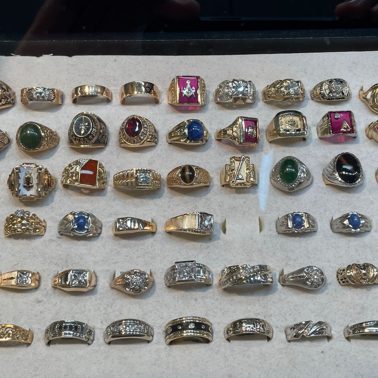 Collection of gold and silver men's rings displayed at Oscar’s Estate Jewelry.