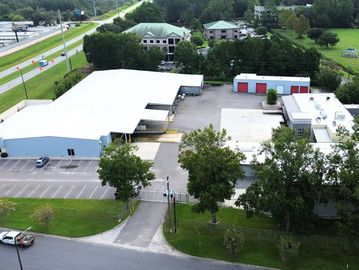 Aerial view of an industrial building complex with parking lots and greenery.