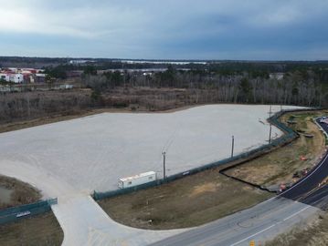 Empty construction site with surrounding roads and forest.