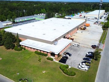 Aerial view of a large industrial warehouse complex with parked cars.