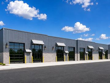 Modern industrial building with large glass doors under a blue sky.