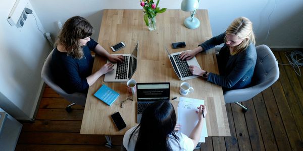 Women sitting around a table with laptops 