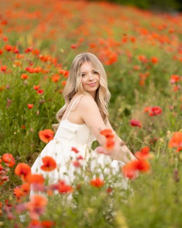 Young woman in a white dress among poppies.