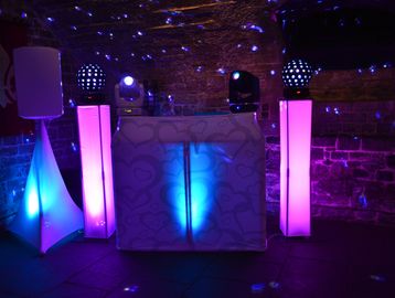 Evening Wedding Setup
Description: White DJ booth with pink and blue uplighting in stone venue.