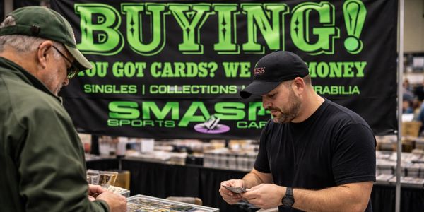 Two men examining sports cards at a trading card booth.