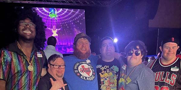 Group of friends smiling at a party with colorful lights.