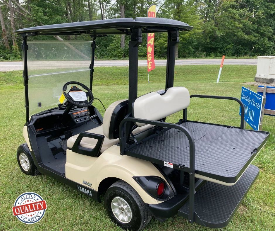 Beige Yamaha golf cart with black roof and rear cargo platform.