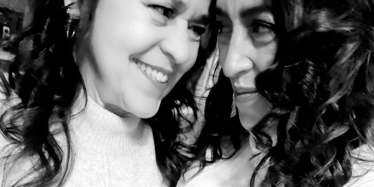 two dark haired women, mother and daughter in white dressy shirts. Smiling
