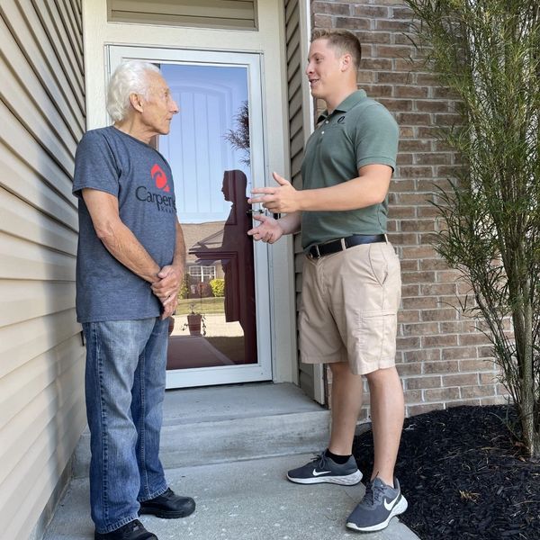 Lux Lawn Care worker speaking with customer in Brownsburg, IN about grass mowing and lawn care.