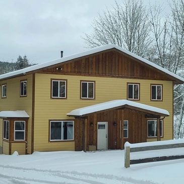 Snow-covered house with Hardie siding and cedar trim. Cedar board and batten siding in the gables.