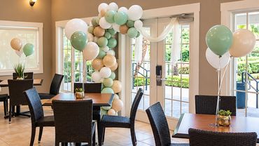 Elegant dining room event setup with a long banquet table surrounded by black dining chairs and flan