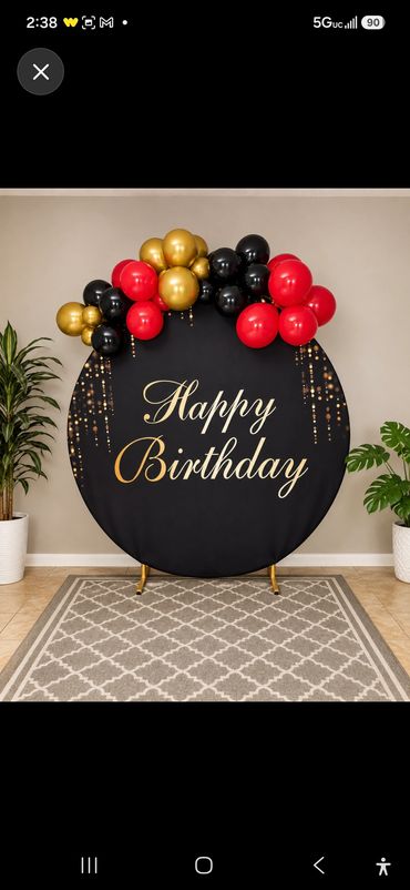 Round black Happy Birthday backdrop with red, gold and black balloon garland.